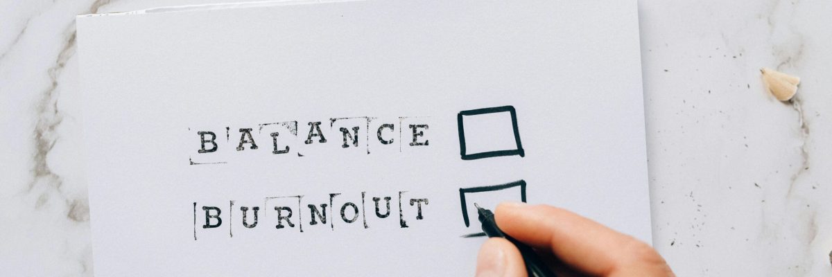 pexels-photo-6837777-6837777 Close-up of a hand hovering over a checklist with options for balance or burnout, symbolizing stress and choice.